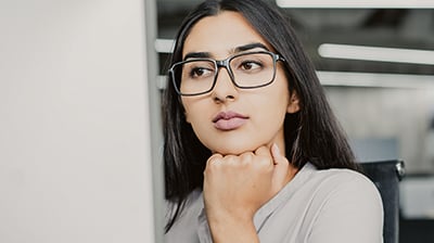 A woman looking forward seriously while resting her fist under her chin 